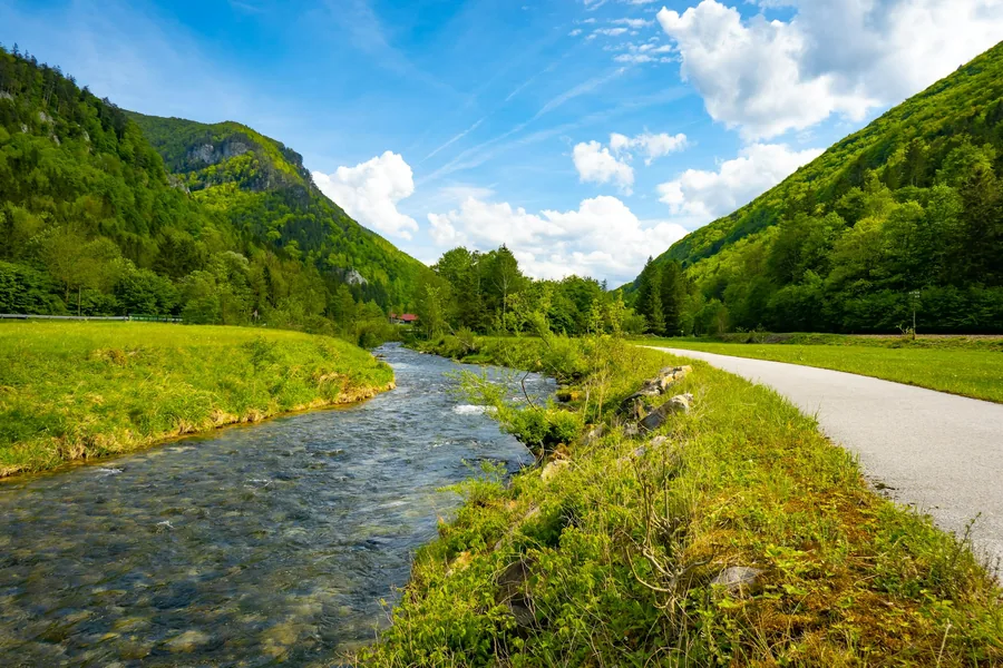Fluss mit Uferweg in einem grünen Tal
